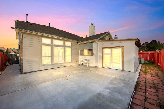 back house at dusk featuring a patio