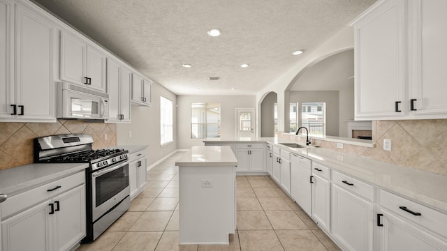 kitchen featuring a center island, white appliances, sink, and light tile patterned floors