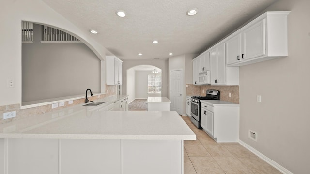 kitchen featuring white cabinetry, sink, kitchen peninsula, light tile patterned flooring, and stainless steel range with gas stovetop