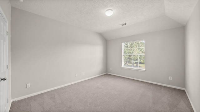 carpeted spare room with a textured ceiling and vaulted ceiling