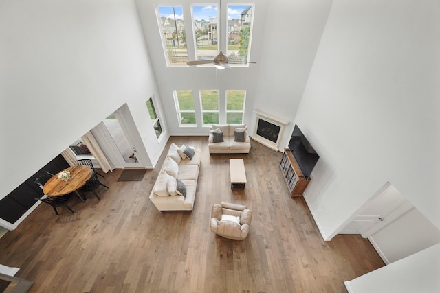 living room featuring a high ceiling, ceiling fan, and light hardwood / wood-style flooring