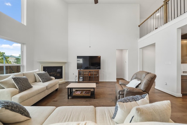 living room with a towering ceiling, ceiling fan, and dark hardwood / wood-style floors