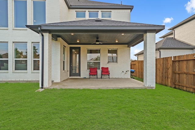 rear view of property featuring ceiling fan, a patio, and a yard