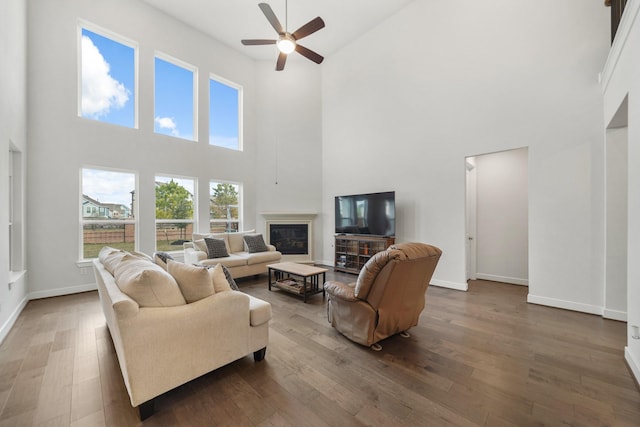 living room featuring a towering ceiling, dark hardwood / wood-style flooring, and ceiling fan