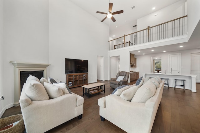 living room featuring a towering ceiling, ceiling fan, and dark hardwood / wood-style flooring