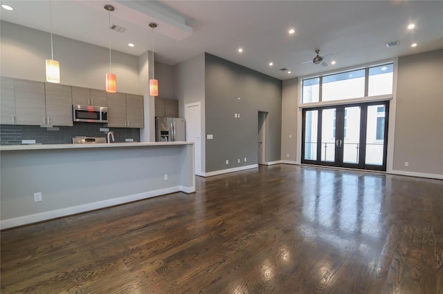 unfurnished living room with french doors, ceiling fan, sink, a high ceiling, and dark hardwood / wood-style floors