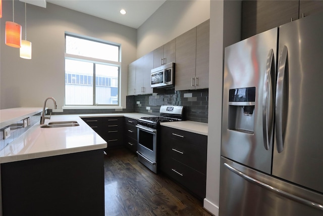 kitchen featuring sink, tasteful backsplash, dark hardwood / wood-style flooring, decorative light fixtures, and appliances with stainless steel finishes