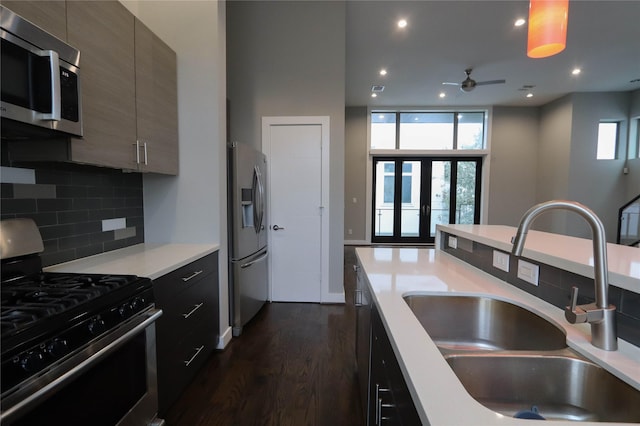 kitchen with appliances with stainless steel finishes, backsplash, ceiling fan, sink, and dark hardwood / wood-style floors