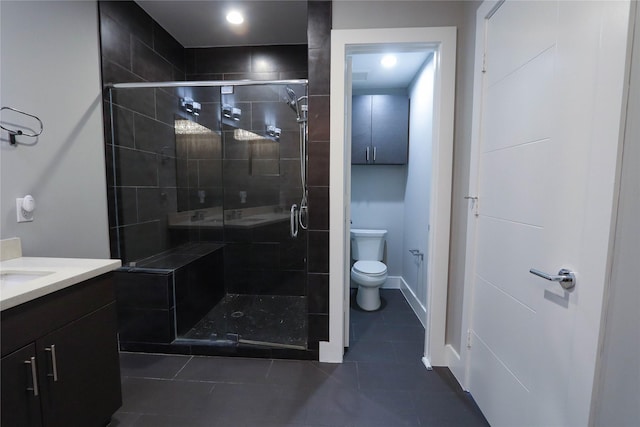 bathroom featuring tile patterned floors, vanity, a shower with shower door, and toilet