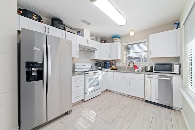 kitchen with light stone countertops, a textured ceiling, stainless steel appliances, sink, and white cabinetry