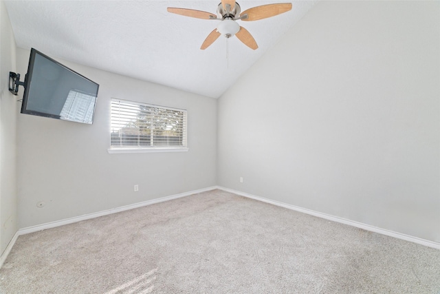 spare room featuring light colored carpet, vaulted ceiling, and ceiling fan