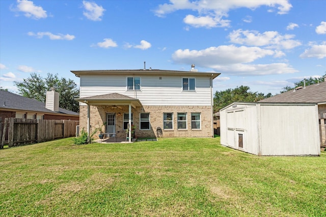 rear view of property with a yard, ceiling fan, and a storage shed