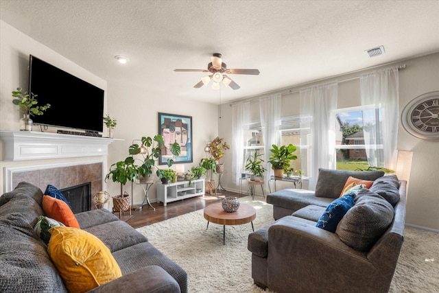 living room featuring a premium fireplace, ceiling fan, dark wood-type flooring, and a textured ceiling