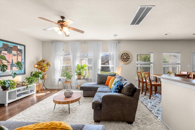 living room with dark hardwood / wood-style flooring, a textured ceiling, and ceiling fan