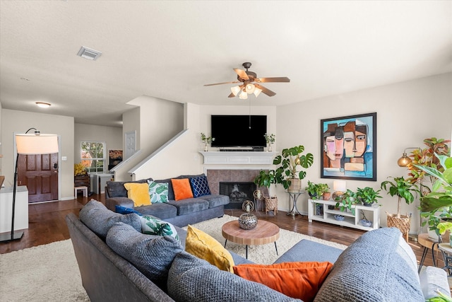 living room with a tile fireplace, dark hardwood / wood-style floors, and ceiling fan