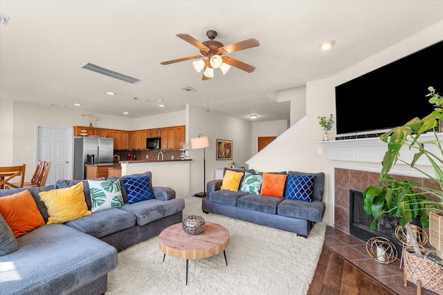 living room with a tile fireplace, ceiling fan, and dark hardwood / wood-style floors