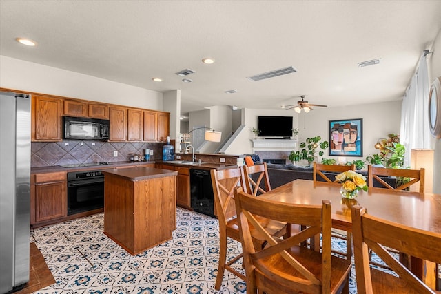 kitchen with light tile patterned flooring, black appliances, decorative backsplash, ceiling fan, and a kitchen island