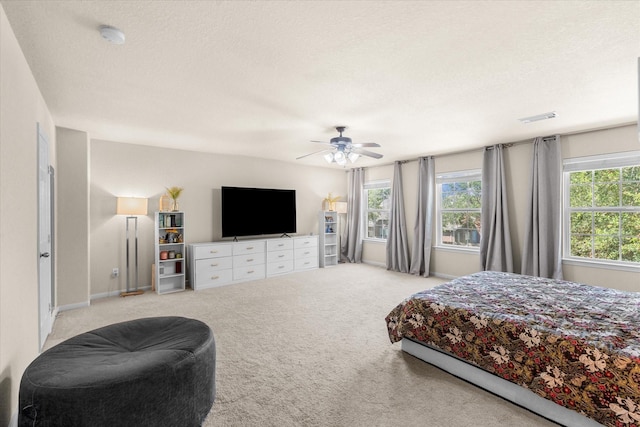 bedroom featuring multiple windows, ceiling fan, light colored carpet, and a textured ceiling