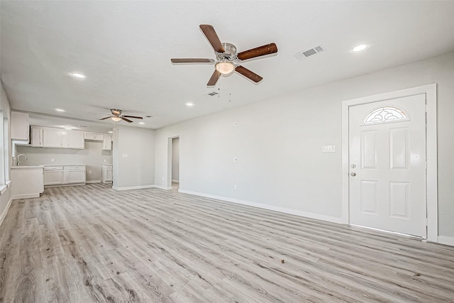 unfurnished living room with ceiling fan, sink, and light hardwood / wood-style floors