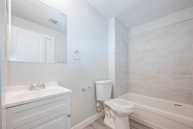 full bathroom featuring vanity, tiled shower / bath combo, toilet, a textured ceiling, and wood-type flooring