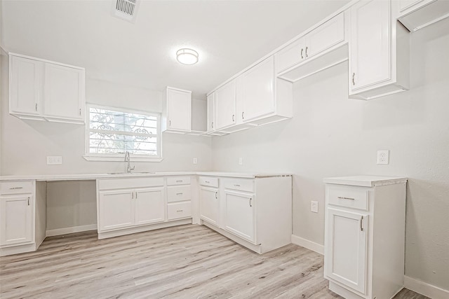 kitchen featuring sink, white cabinets, and light wood-type flooring