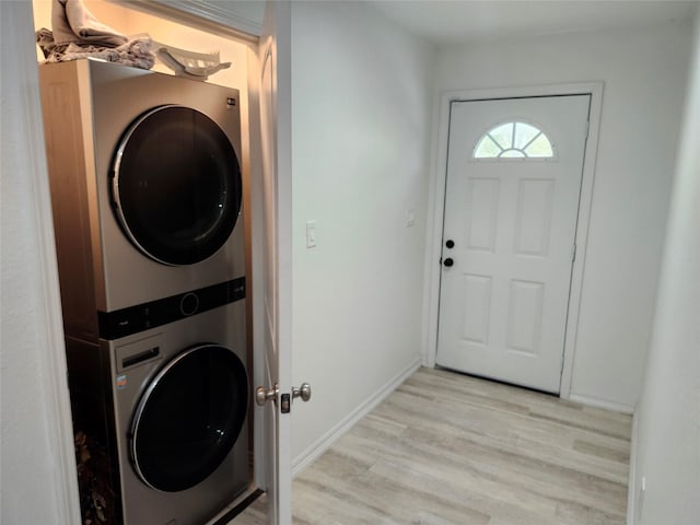 laundry area with light hardwood / wood-style floors and stacked washer and dryer