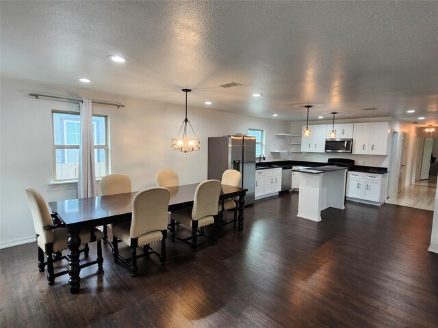 dining space with sink, a notable chandelier, dark hardwood / wood-style flooring, and a textured ceiling