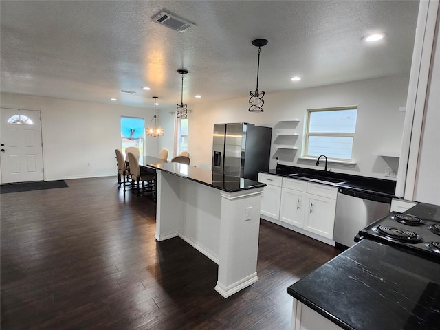 kitchen featuring appliances with stainless steel finishes, sink, decorative light fixtures, a center island, and white cabinetry