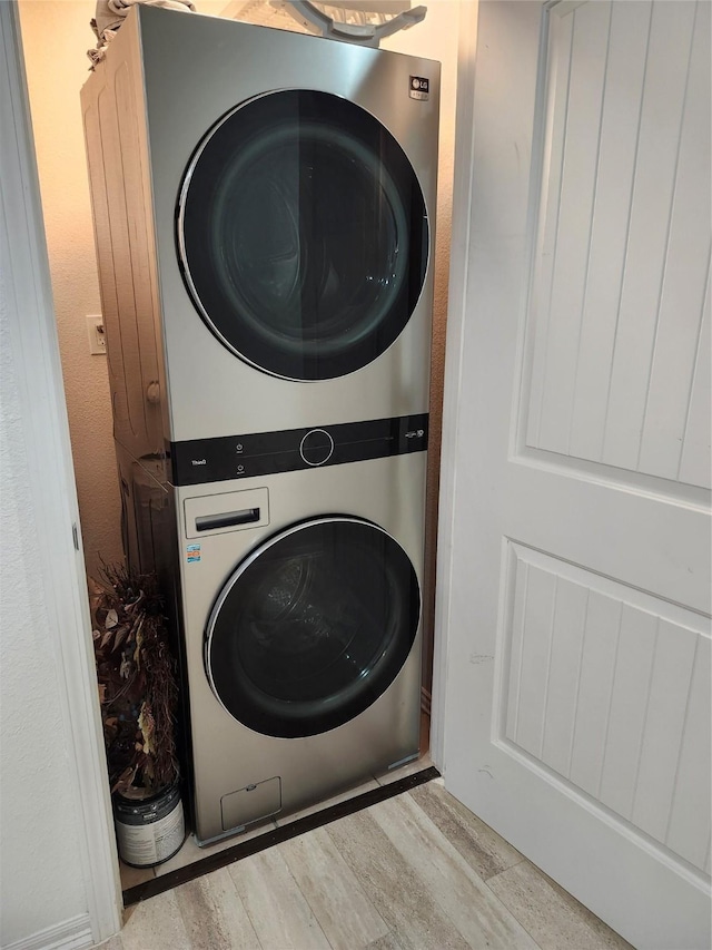 clothes washing area with light hardwood / wood-style floors and stacked washing maching and dryer