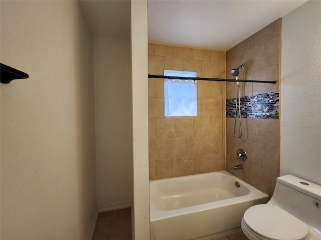 bathroom with toilet, tile patterned flooring, and tiled shower / bath