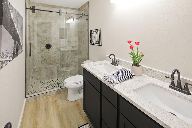 bathroom with hardwood / wood-style floors, vanity, toilet, and a shower with door