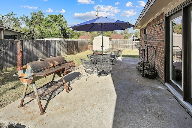 view of patio with a shed and a grill