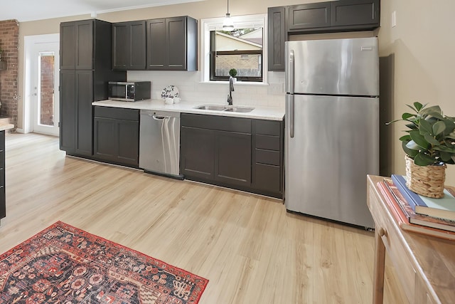 kitchen featuring pendant lighting, stainless steel appliances, light hardwood / wood-style flooring, and sink