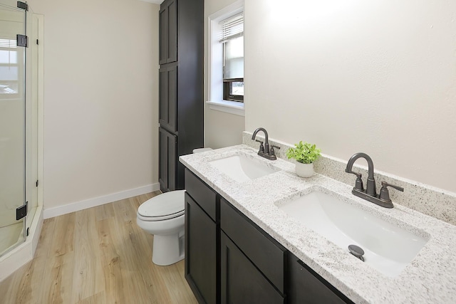 bathroom with hardwood / wood-style floors, vanity, a shower with shower door, and toilet