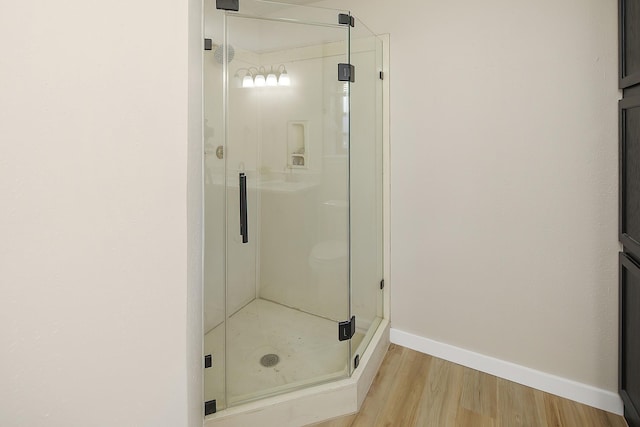 bathroom with wood-type flooring and an enclosed shower