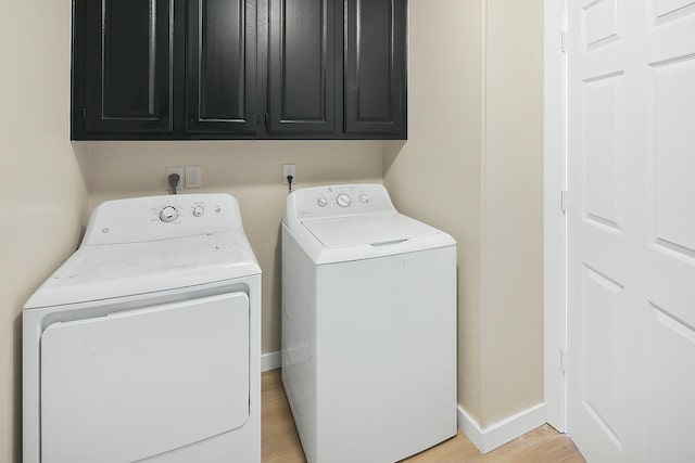 laundry room with light hardwood / wood-style floors, cabinets, and independent washer and dryer