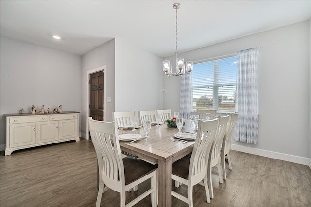 dining area with wood-type flooring and an inviting chandelier