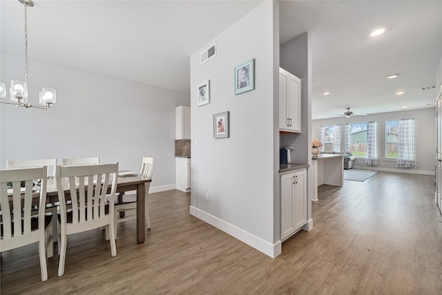 dining area featuring light hardwood / wood-style flooring and ceiling fan with notable chandelier