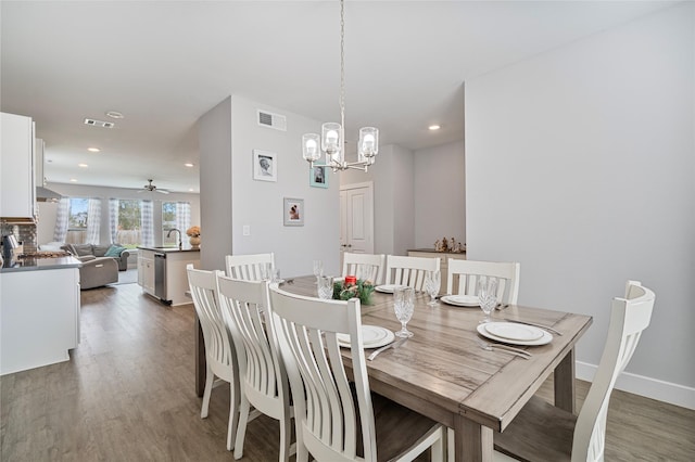 dining area with ceiling fan with notable chandelier, dark hardwood / wood-style floors, and sink