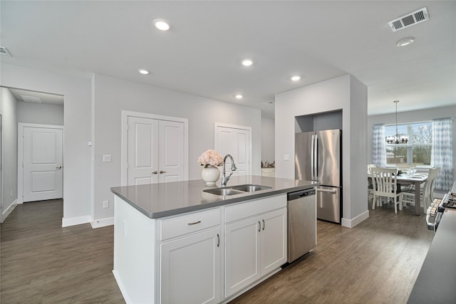 kitchen featuring white cabinets, sink, an island with sink, decorative light fixtures, and stainless steel appliances