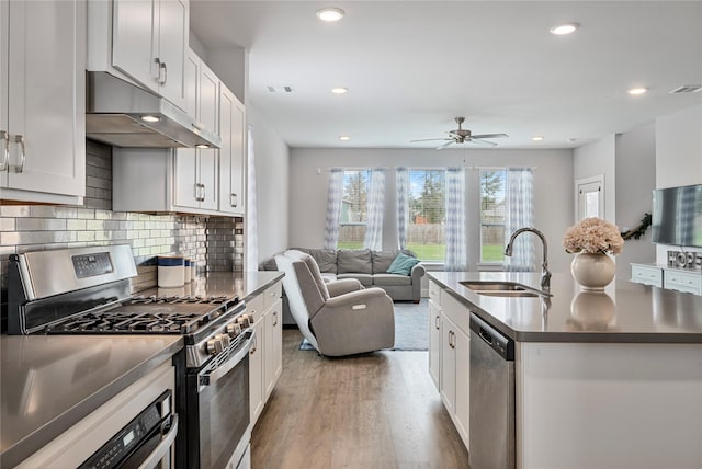 kitchen with sink, stainless steel appliances, an island with sink, white cabinets, and hardwood / wood-style flooring