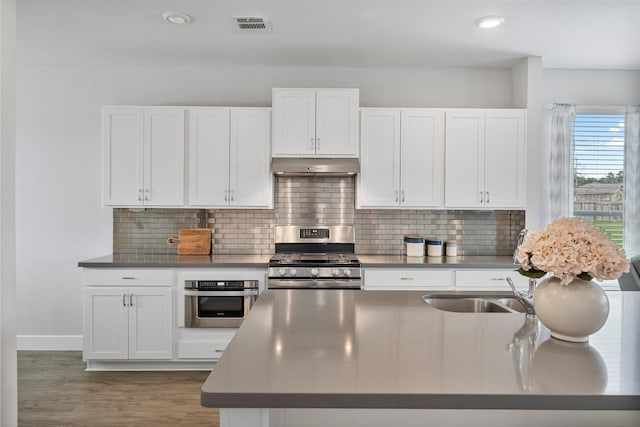 kitchen featuring decorative backsplash, stainless steel appliances, sink, dark hardwood / wood-style floors, and white cabinetry