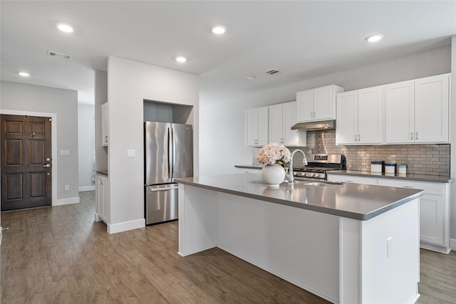 kitchen featuring backsplash, a kitchen island with sink, white cabinets, light hardwood / wood-style floors, and stainless steel appliances