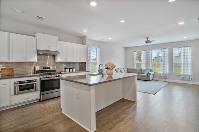 kitchen featuring white cabinets, sink, light hardwood / wood-style flooring, an island with sink, and stainless steel appliances