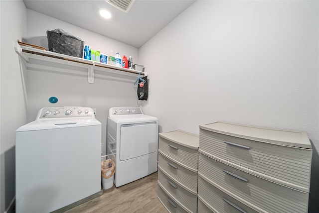 laundry room with light hardwood / wood-style flooring and washing machine and clothes dryer