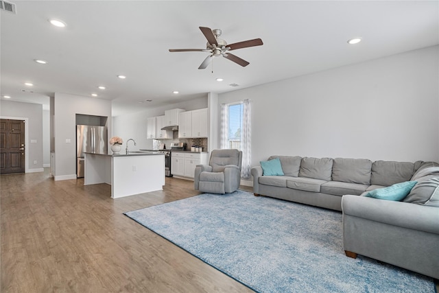 living room featuring ceiling fan, sink, and light hardwood / wood-style floors