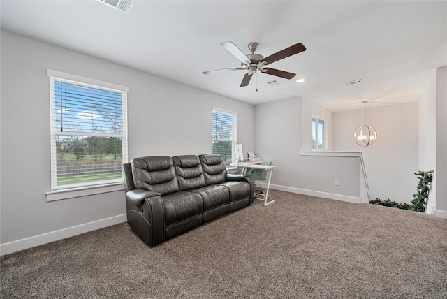 living room with carpet flooring, ceiling fan with notable chandelier, and a healthy amount of sunlight