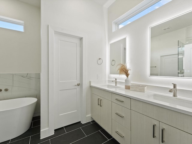 bathroom featuring tile patterned flooring, vanity, a tub to relax in, and tile walls