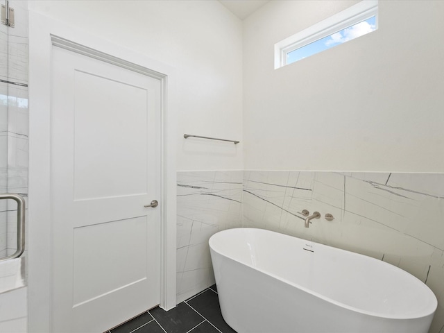 bathroom featuring tile patterned flooring, a bathtub, and tile walls