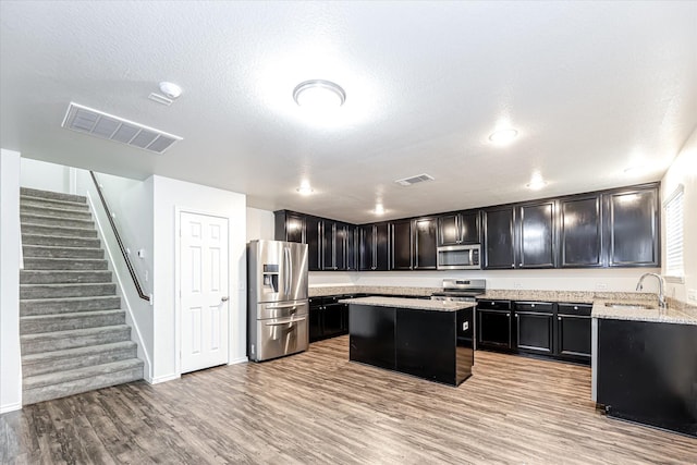 kitchen featuring light stone counters, sink, light wood-type flooring, and appliances with stainless steel finishes